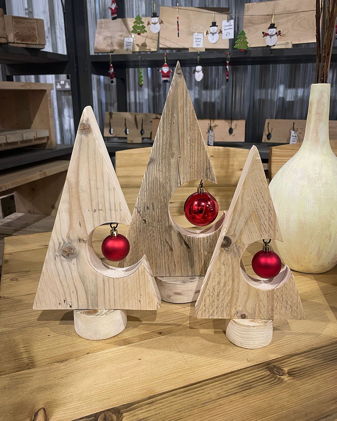 Make Wooden Christmas Trees: 7 DIY Projects from Scrap to Yard 1 Three small wooden Christmas trees with red ornaments sitting on a wooden table.
