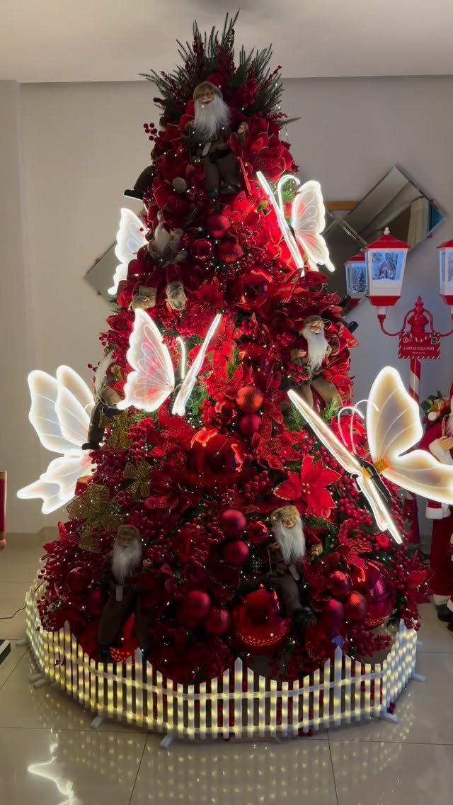 21 Most Beautiful Christmas Trees for Bold and Cozy Looks 12 A red Christmas tree decorated with large glowing white butterflies and red floral ornaments.