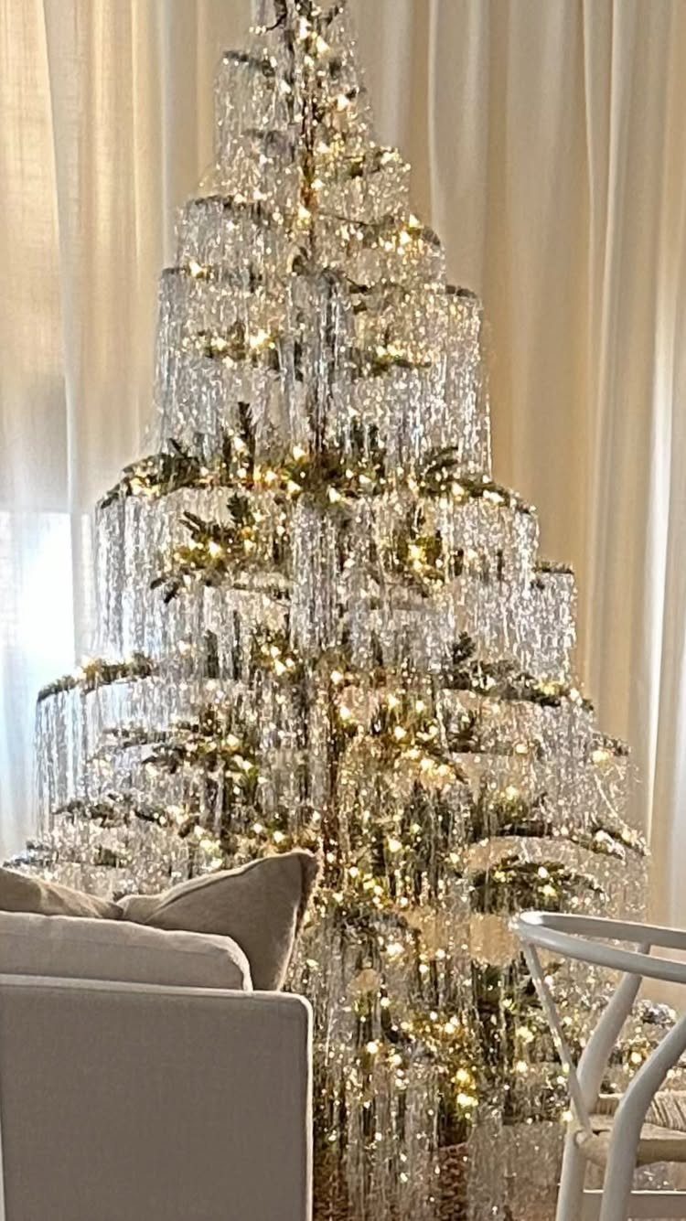 21 Most Beautiful Christmas Trees for Bold and Cozy Looks 11 A Christmas tree draped in long, shimmering silver tinsel strands and warm glowing lights.