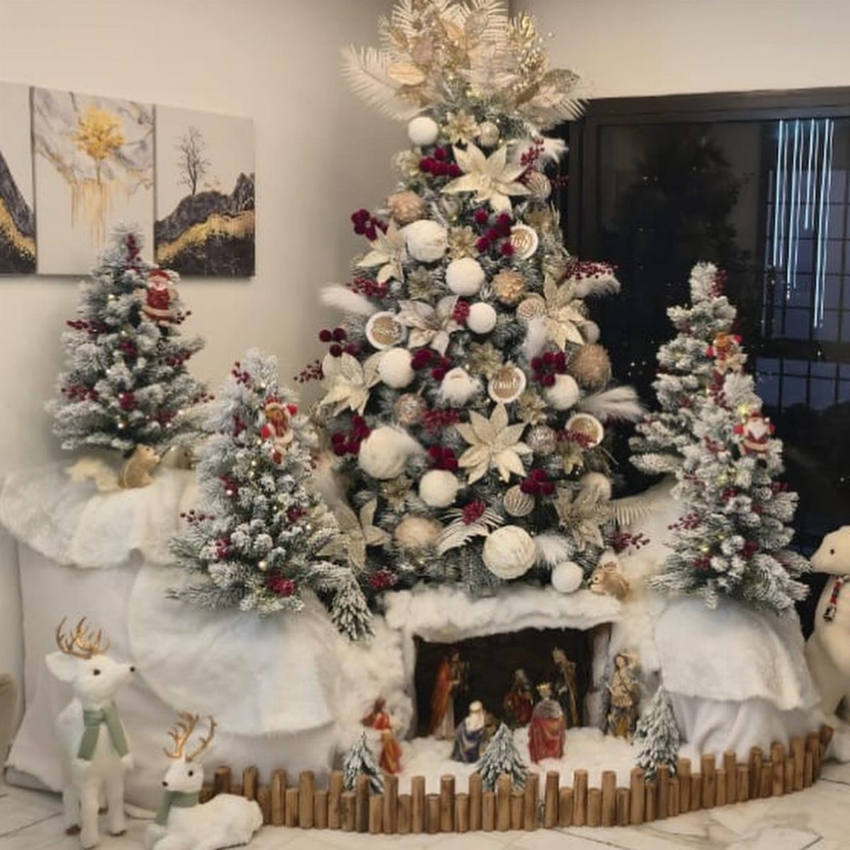 21 Most Beautiful Christmas Trees for Bold and Cozy Looks 16 A large flocked Christmas tree decorated with white poinsettias and gold ornaments surrounded by smaller trees.