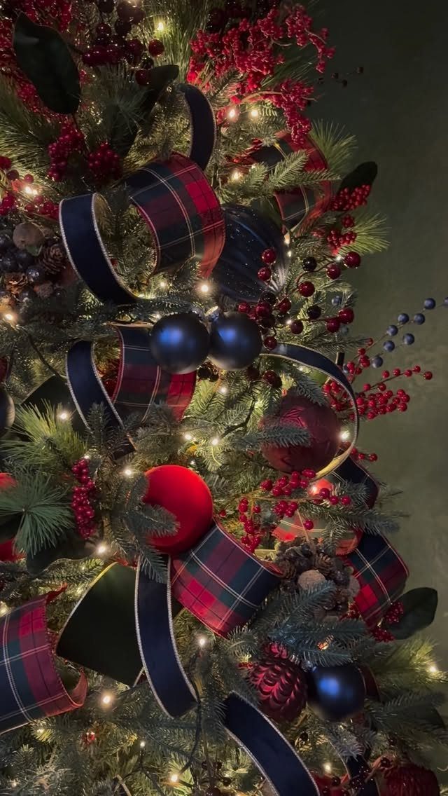 21 Most Beautiful Christmas Trees for Bold and Cozy Looks 3 Christmas tree branches decorated with red berries, plaid ribbons, and dark blue ornaments.