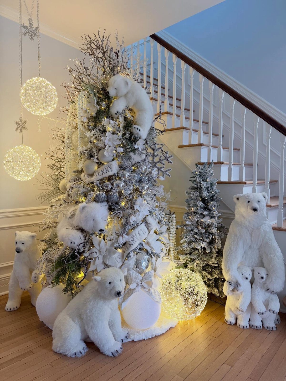 21 Most Beautiful Christmas Trees for Bold and Cozy Looks 13 Silver Christmas tree decorated with white ribbons and polar bear figurines near a staircase.