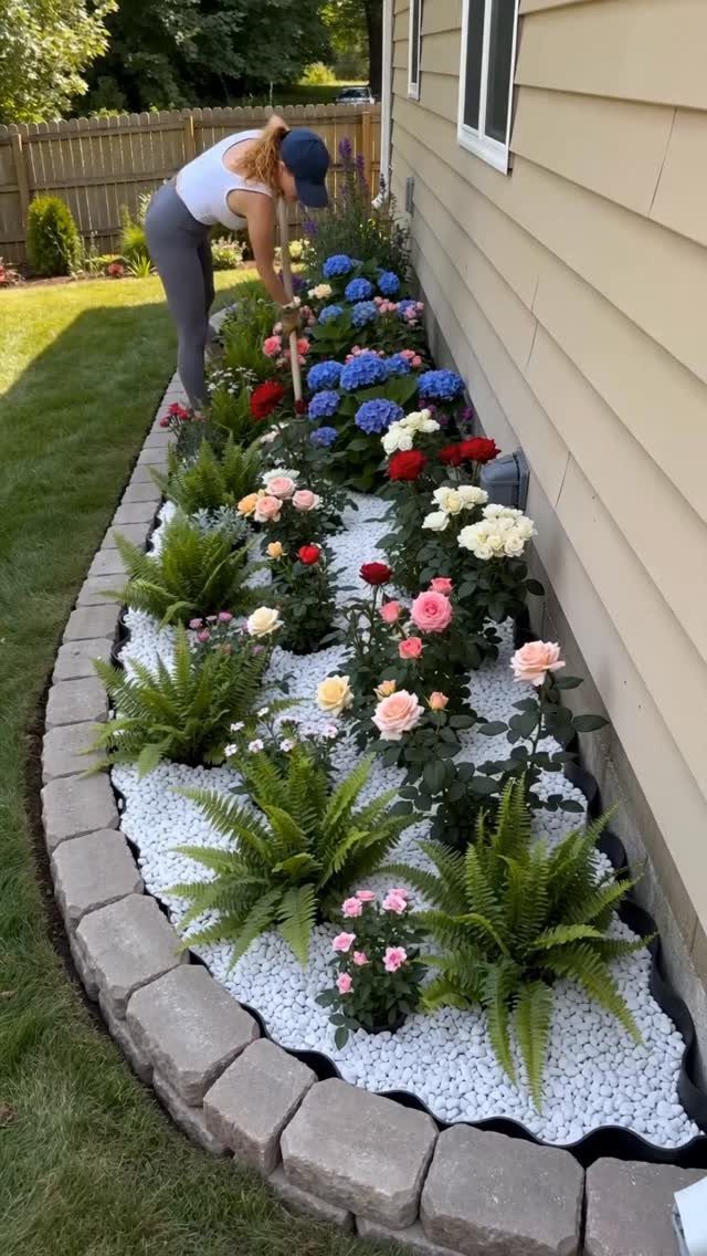 11 Small Flower Bed Ideas for Compact, Handsome Gardens 11 A person gardening in a long flower bed filled with white gravel, ferns, and colorful roses.