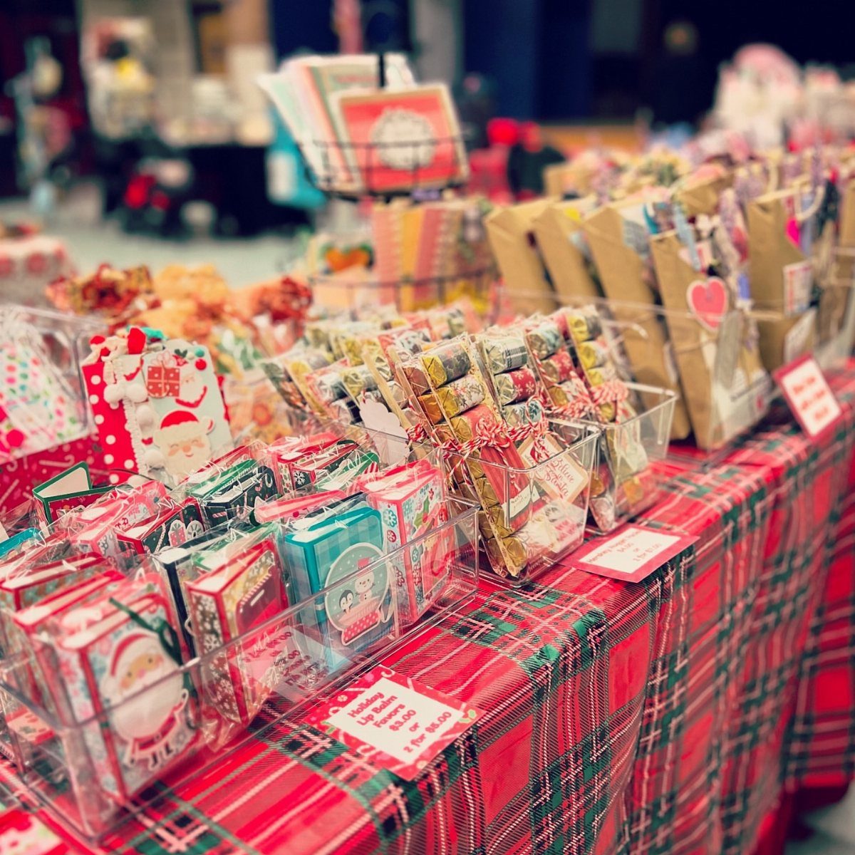 21 Things to Do for Christmas 2026 10 Handmade holiday gifts and small wrapped items displayed on a red plaid tablecloth at a market.