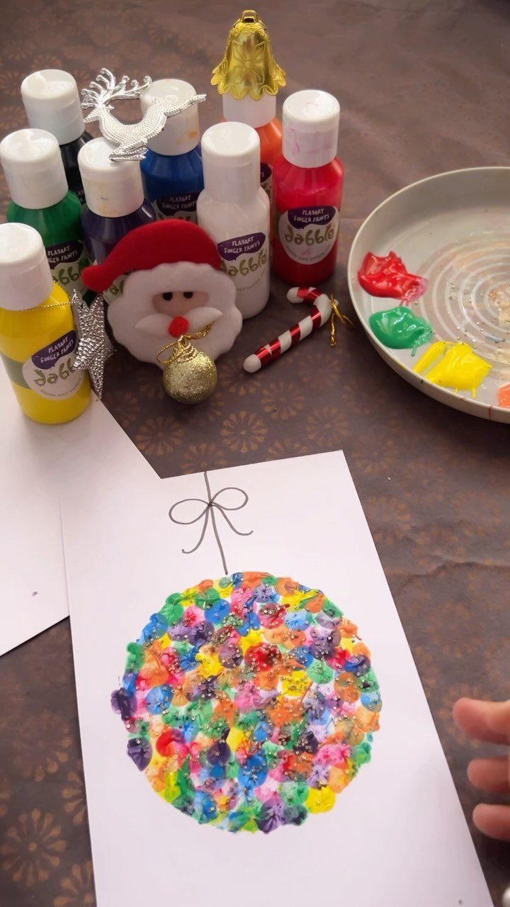 21 Things to Do for Christmas 2026 21 Colorful bubble wrap painting of a Christmas ornament surrounded by paint bottles and a small Santa figure.